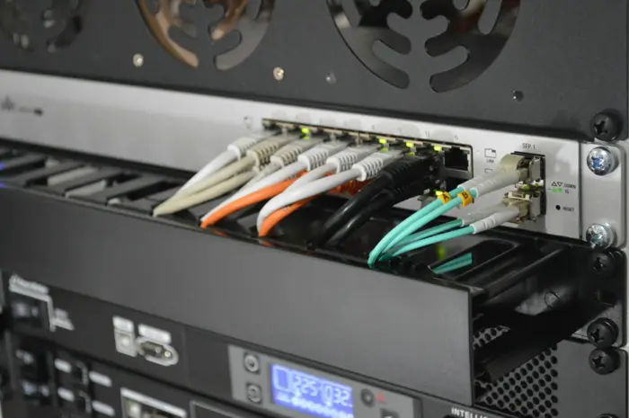 Copper and fibre patch cables connected to a network switch in a server rack.